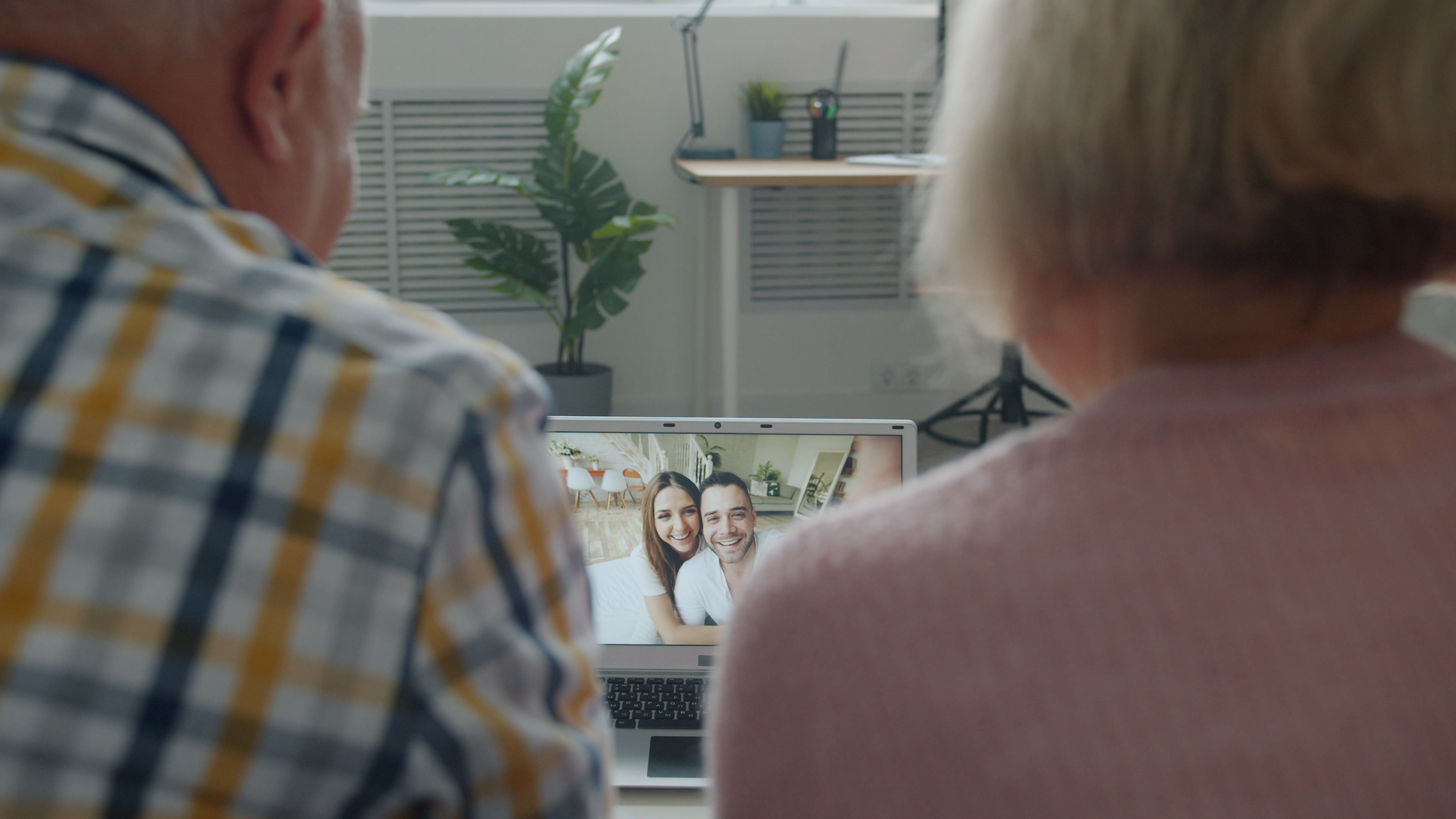 Senior couple talking with family over a laptop video call at home.