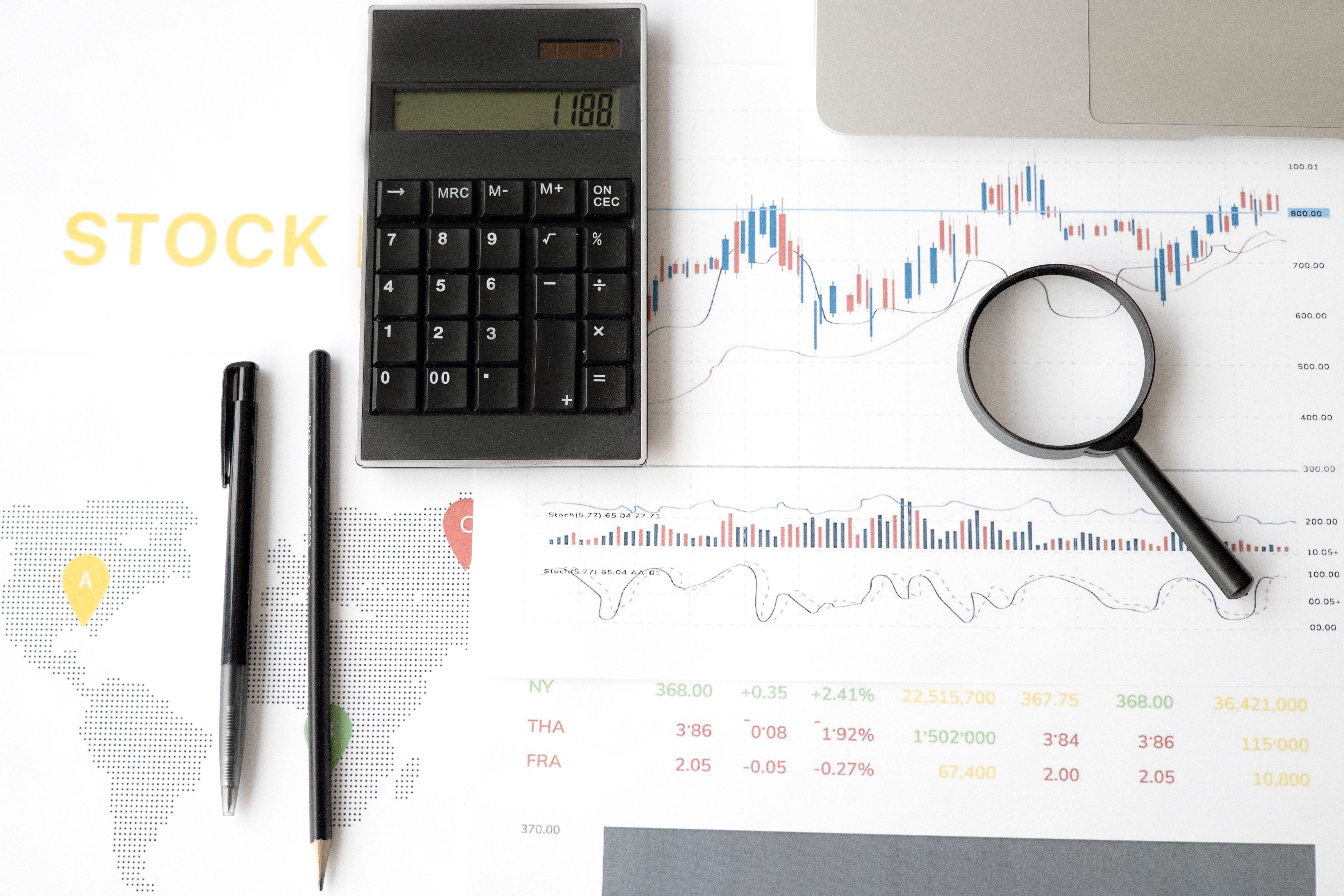 Flat lay of stock market analysis tools including calculator and graphs for financial forecasting