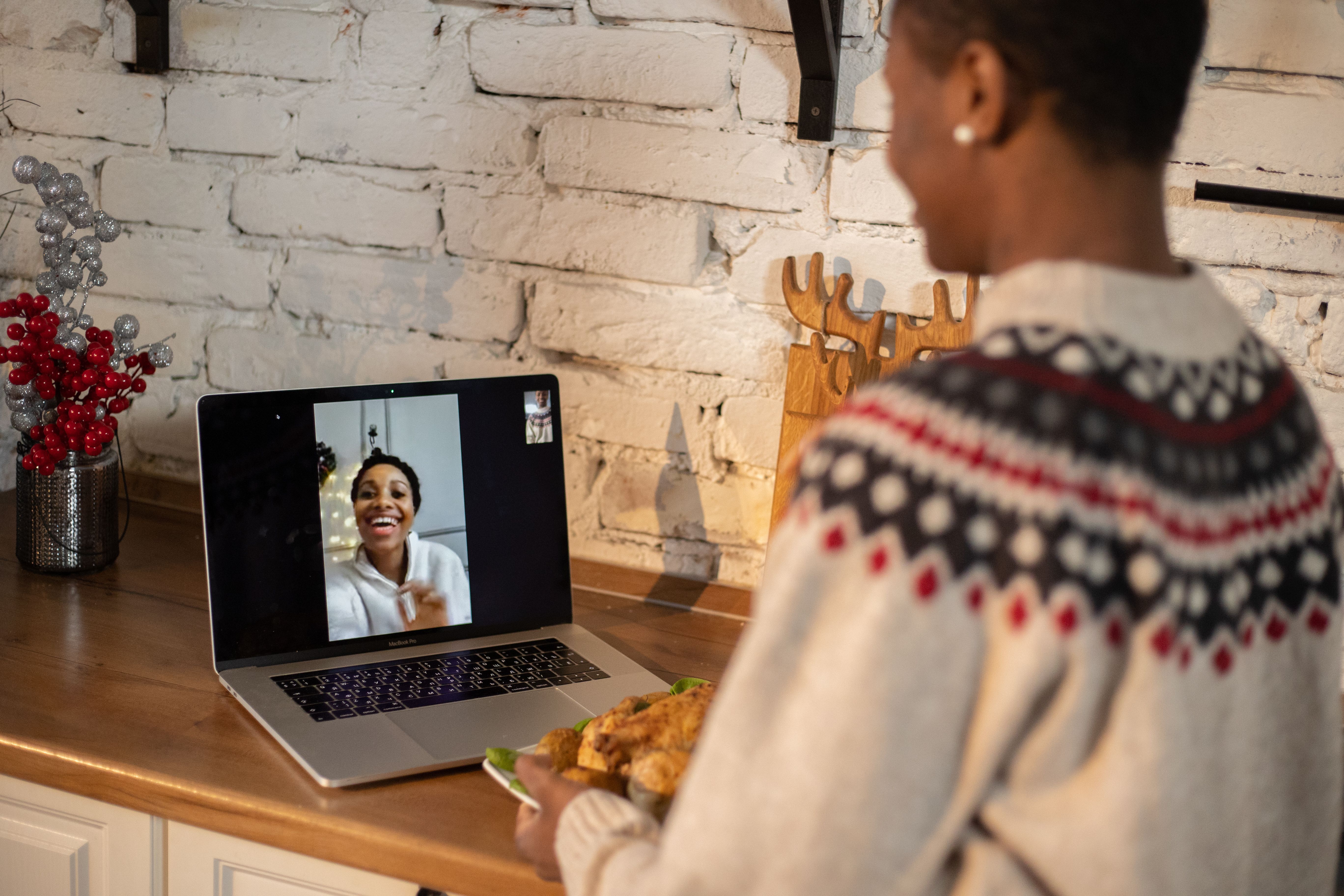 Friends sharing a warm, festive video call, using a screen to feel present at a gathering.