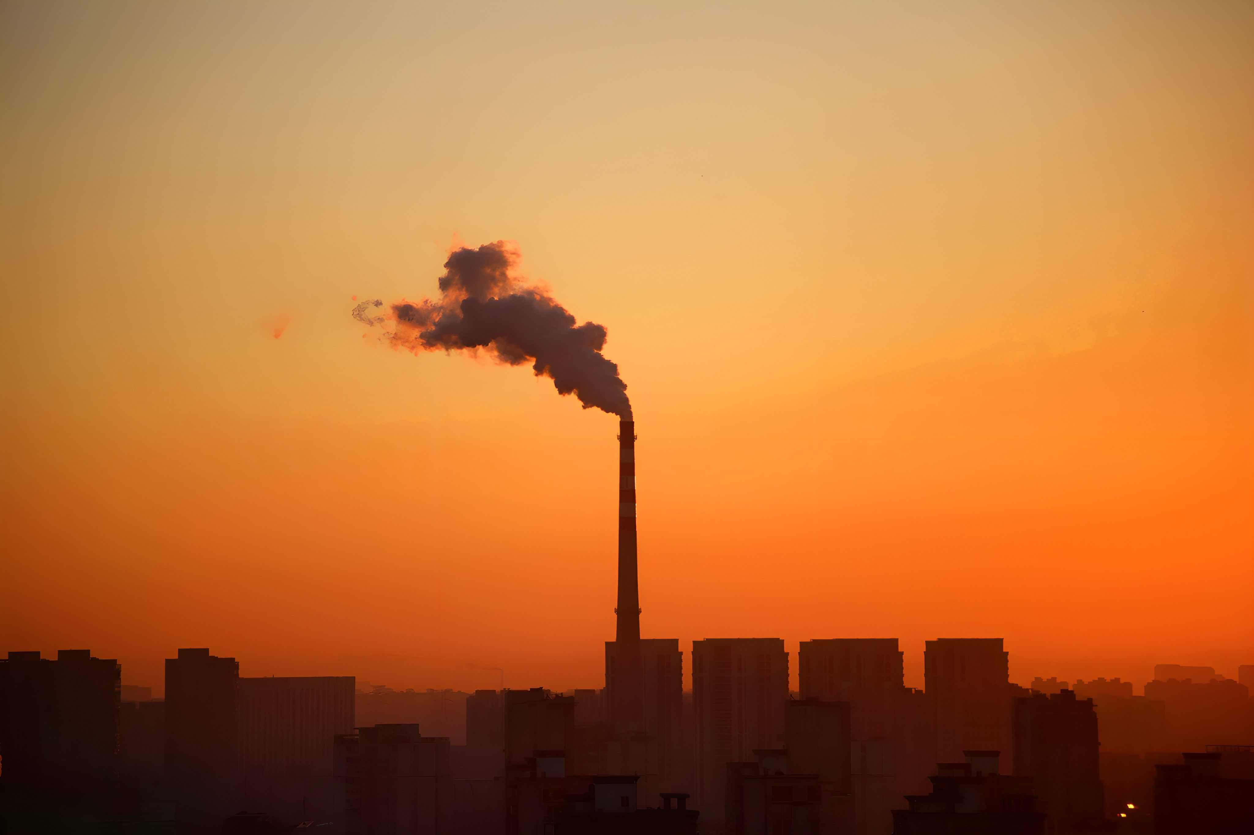 Industrial smokestack emitting smoke at sunset, representing pollution at the center of an environmental case.