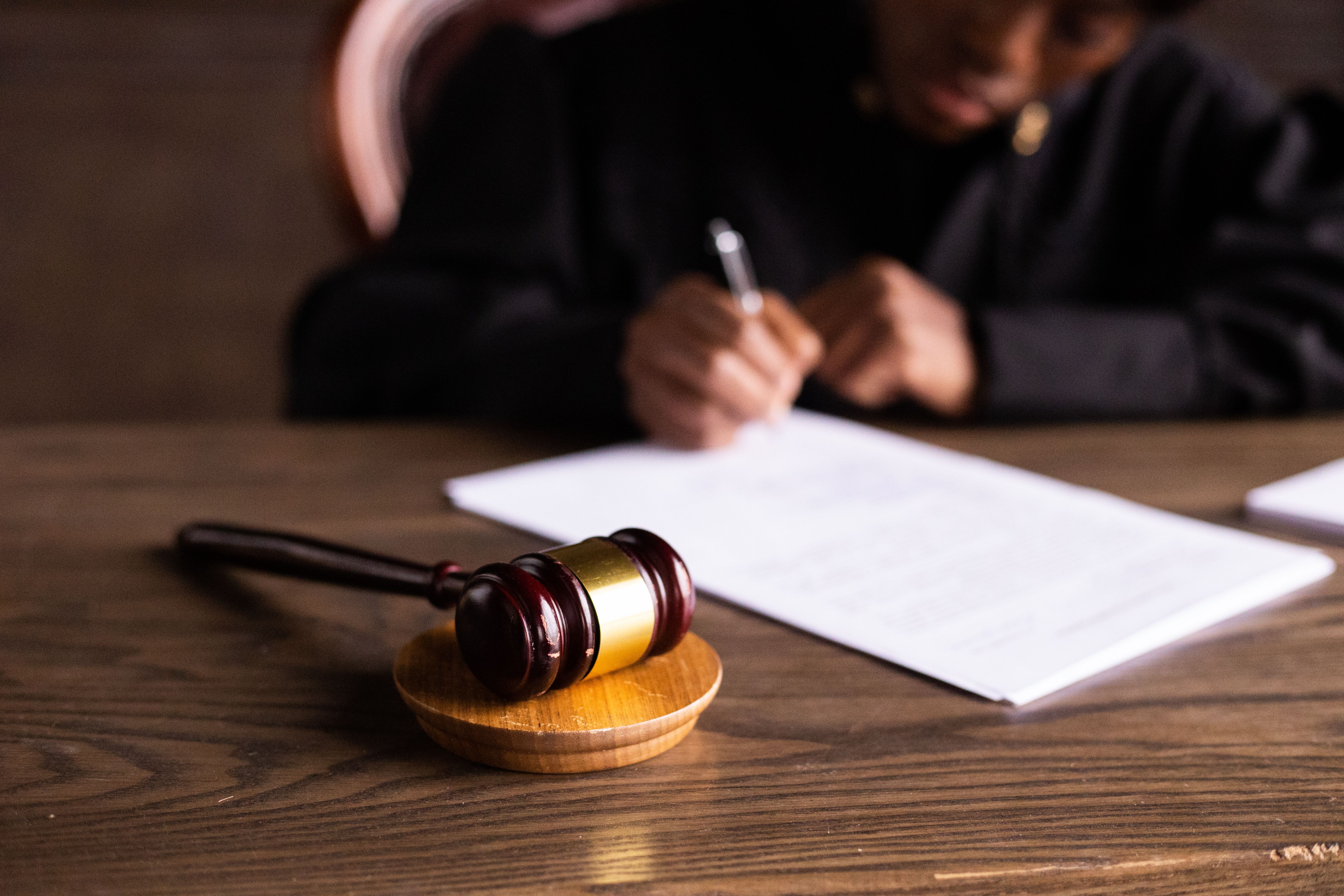 Judge signing documents at a desk with a gavel, representing law and justice